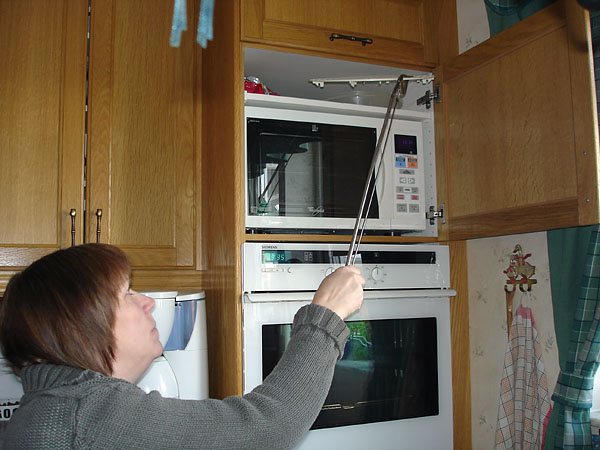 User gets a dish from the upper cabinet using pliers
